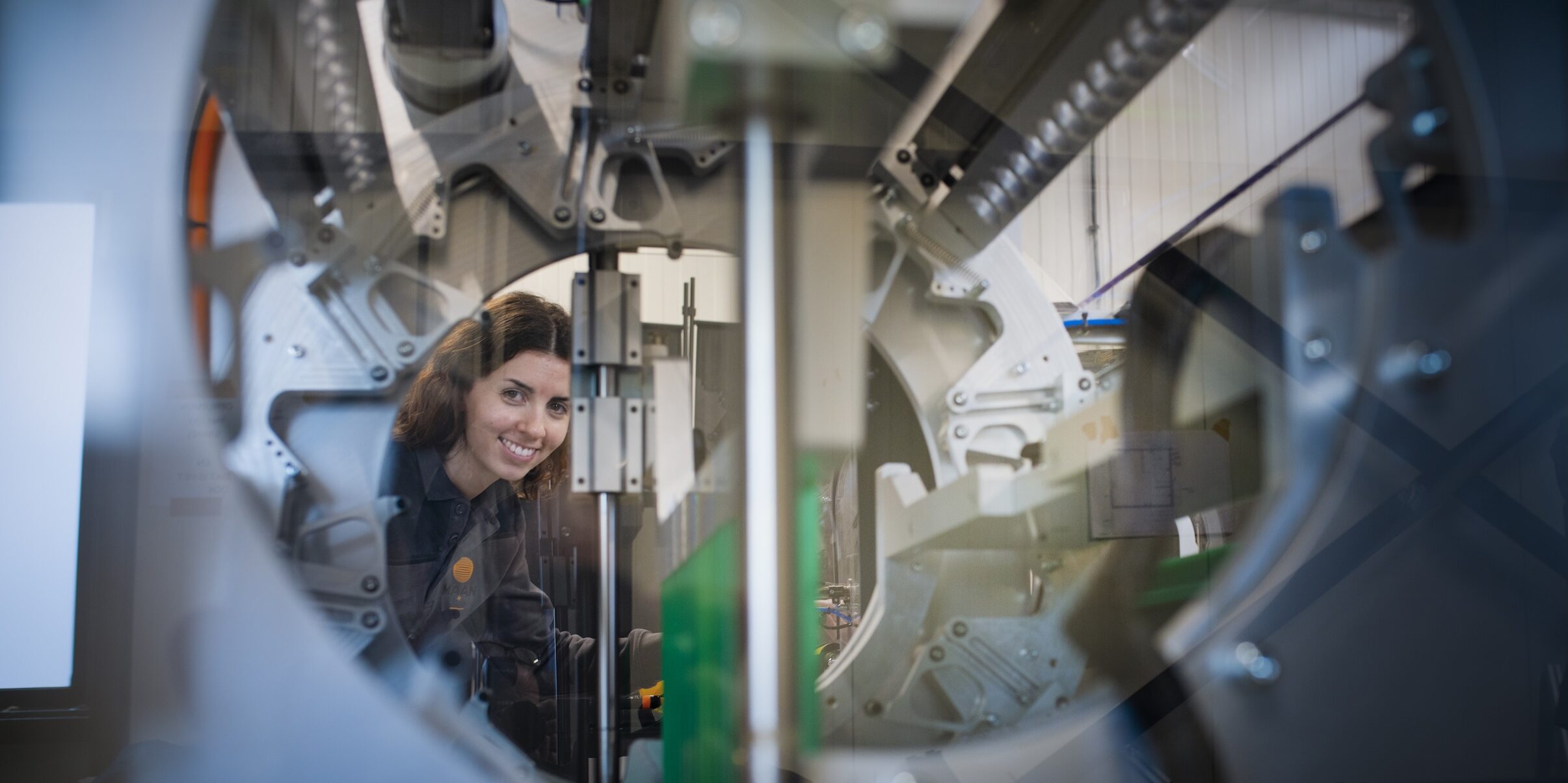 reportage over innovatie en techniek bij de Maan Group in Raalte een jongedame kijkt door de machine richting camera bij de Maan Group in Raalte